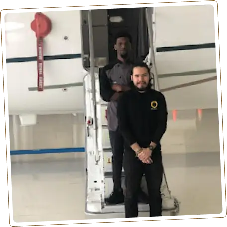 Two men on private jet stairs, one in black.