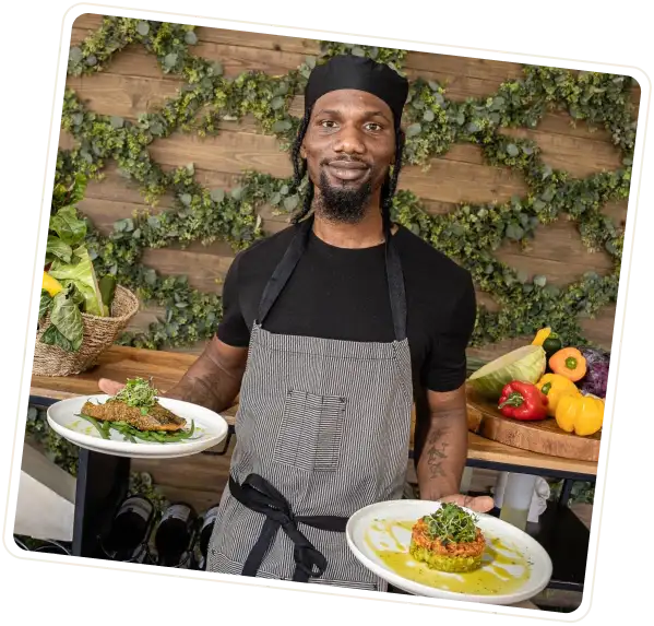 Chef holding two plates of food.